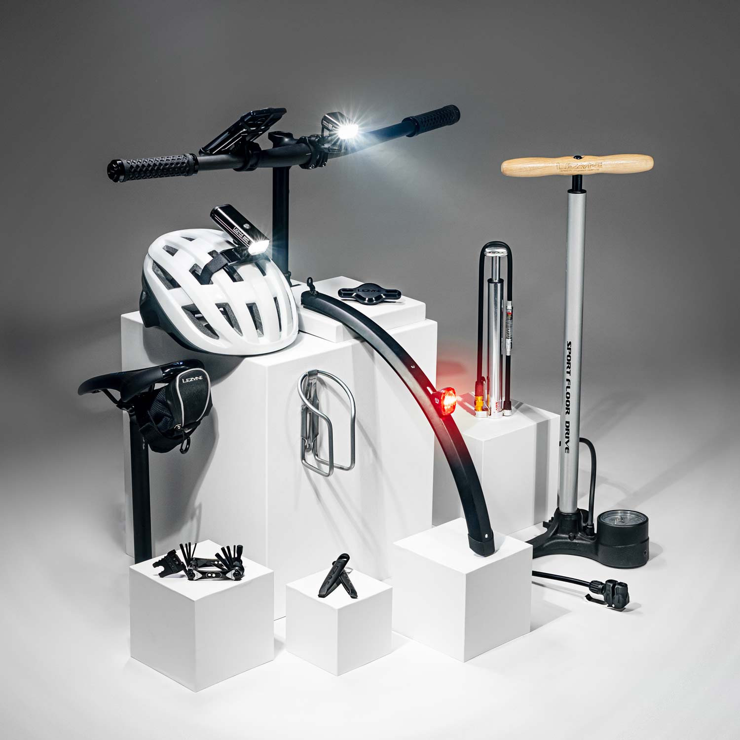 Bicycle tools, bags, lights pumps, and mounts on display podiums with the parts of a bicycle that they attach to.