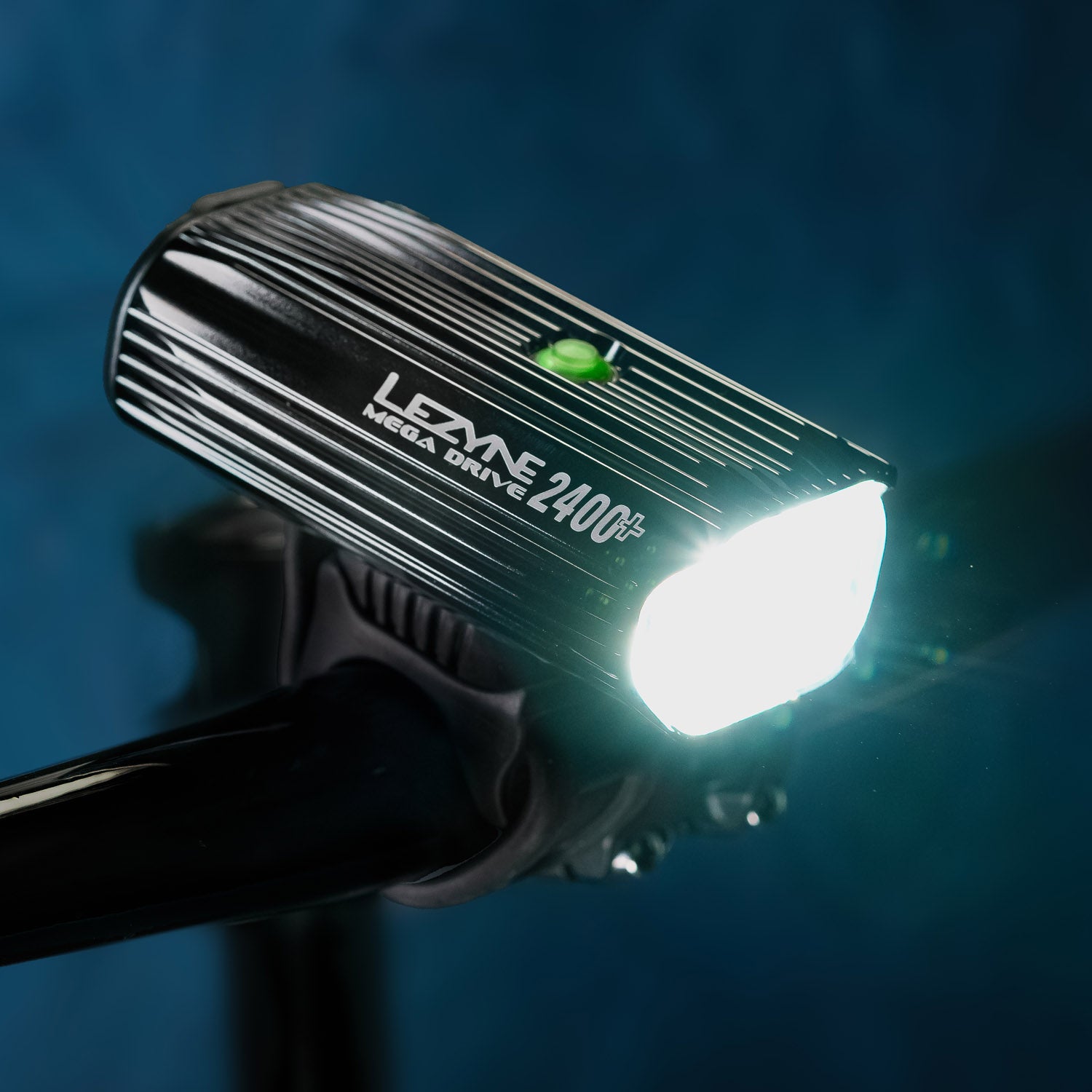 Iso view of Mega Drive 2400+ mounted on MTB handlebar, projecting a powerful LED light beam - ideal for night trails.