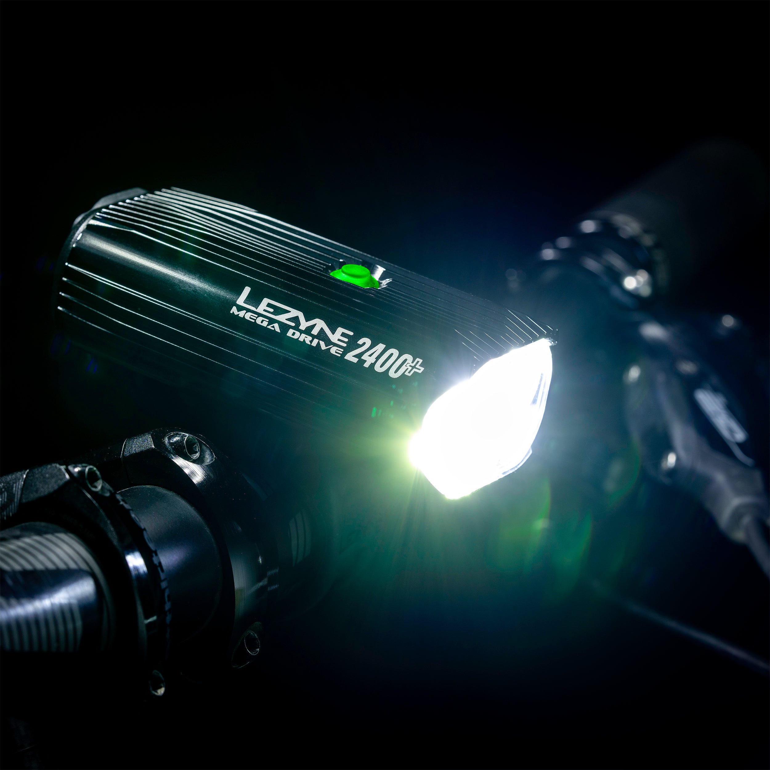 Side view of Mega Drive 2400+ mounted on MTB handlebar, projecting a powerful LED light beam - ideal for night trails.