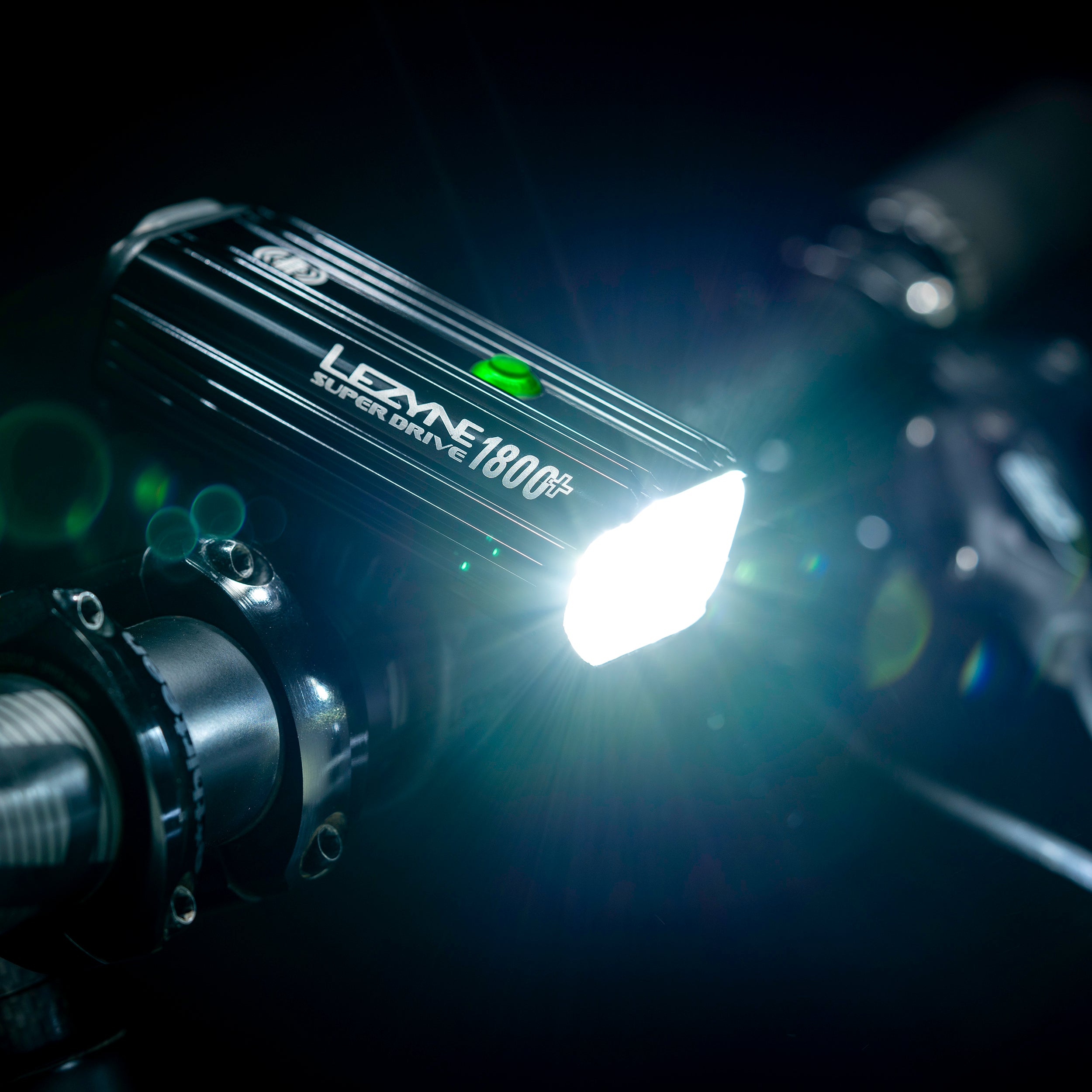 Super Drive 1800+ mounted on MTB handlebar, projecting a powerful LED light beam - perfect for night trail rides.