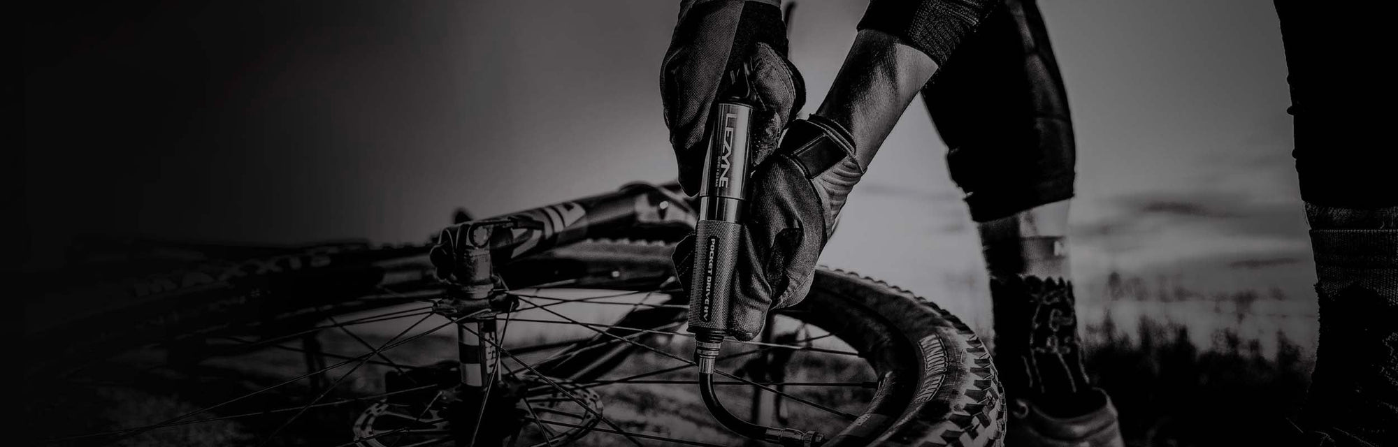 A gloved hand inflating a bicycle tire with a hand pump.