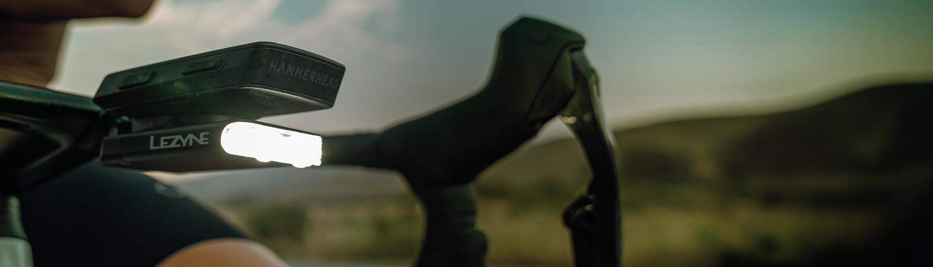 Someone pressing the button on a front light mounted on bicycle handlebars