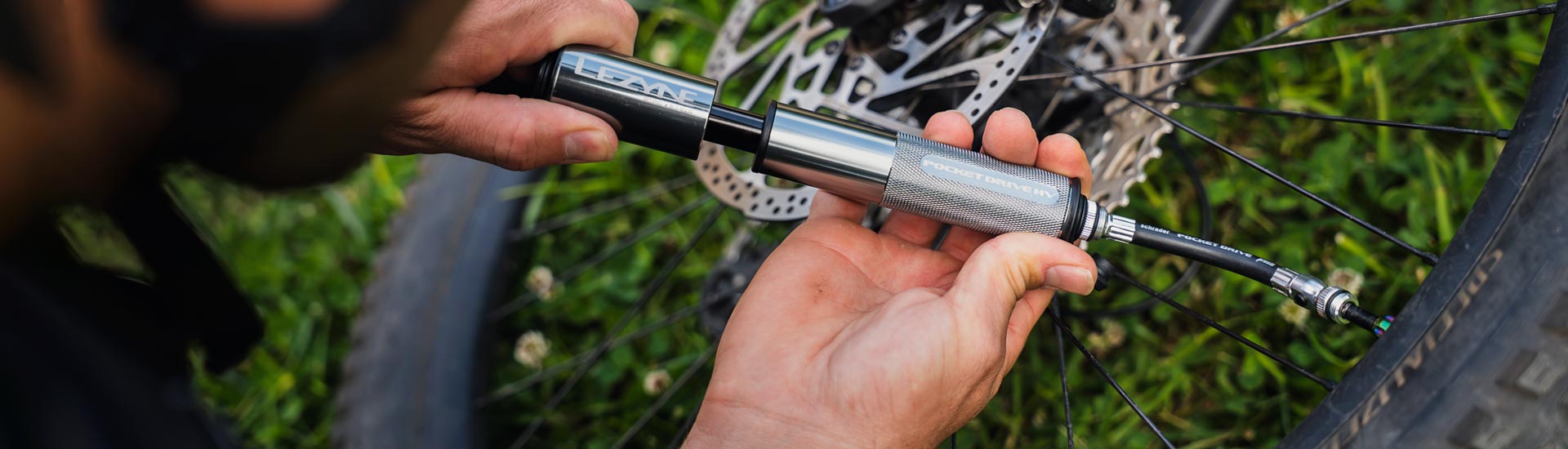 Gloved hands holding a digital pressure gage next to a bicycle tire.