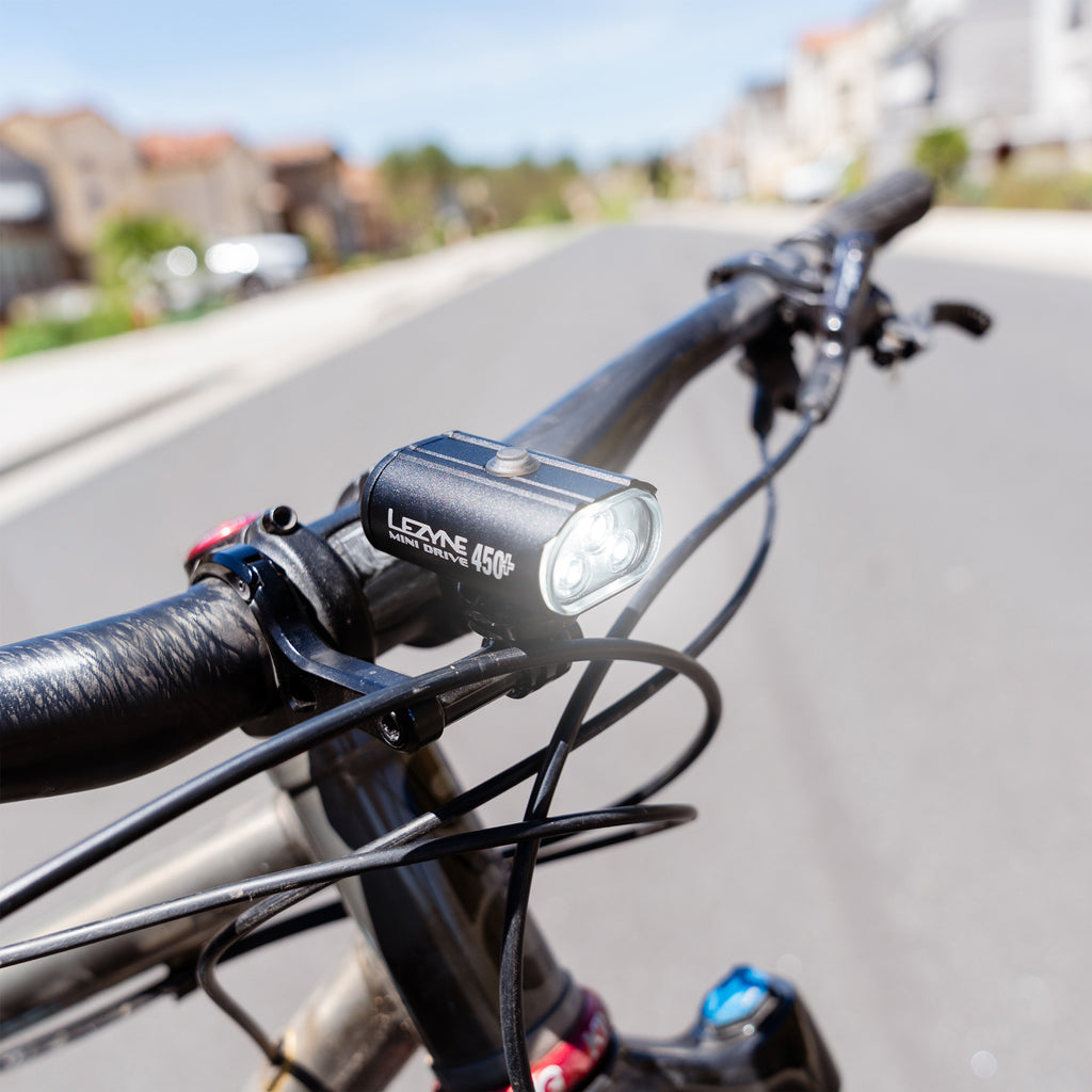 Close-up of the Lezyne Mini Drive 450+ Front mounted securely on a bike handlebar