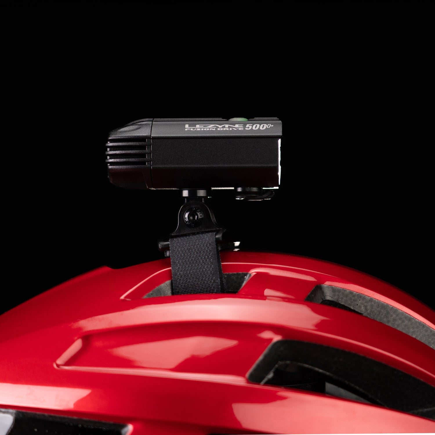 Side close-up studio shot of the Lezyne Helmet Fusion Drive 500+ mounted on a red helmet with Velcro strap