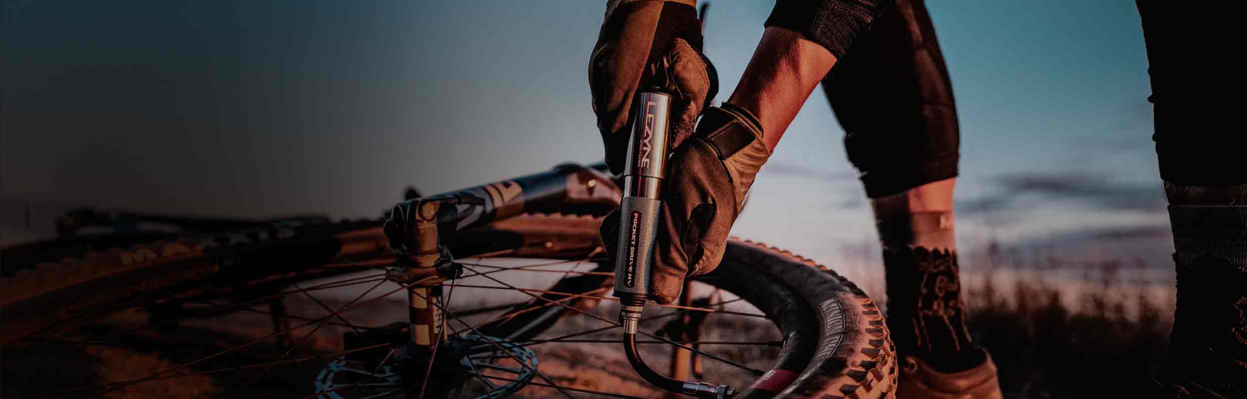 Gloved hands using a hand pump to inflate a bicycle tire.