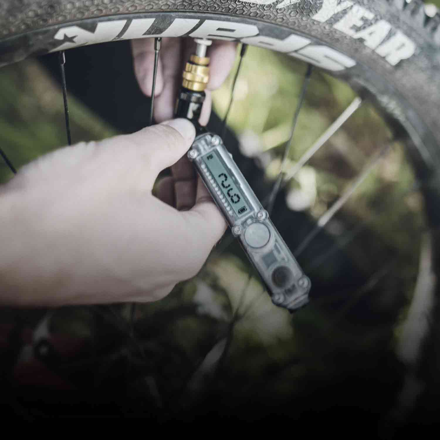 Someone using a digital pressure gauge on a bicycle tire.