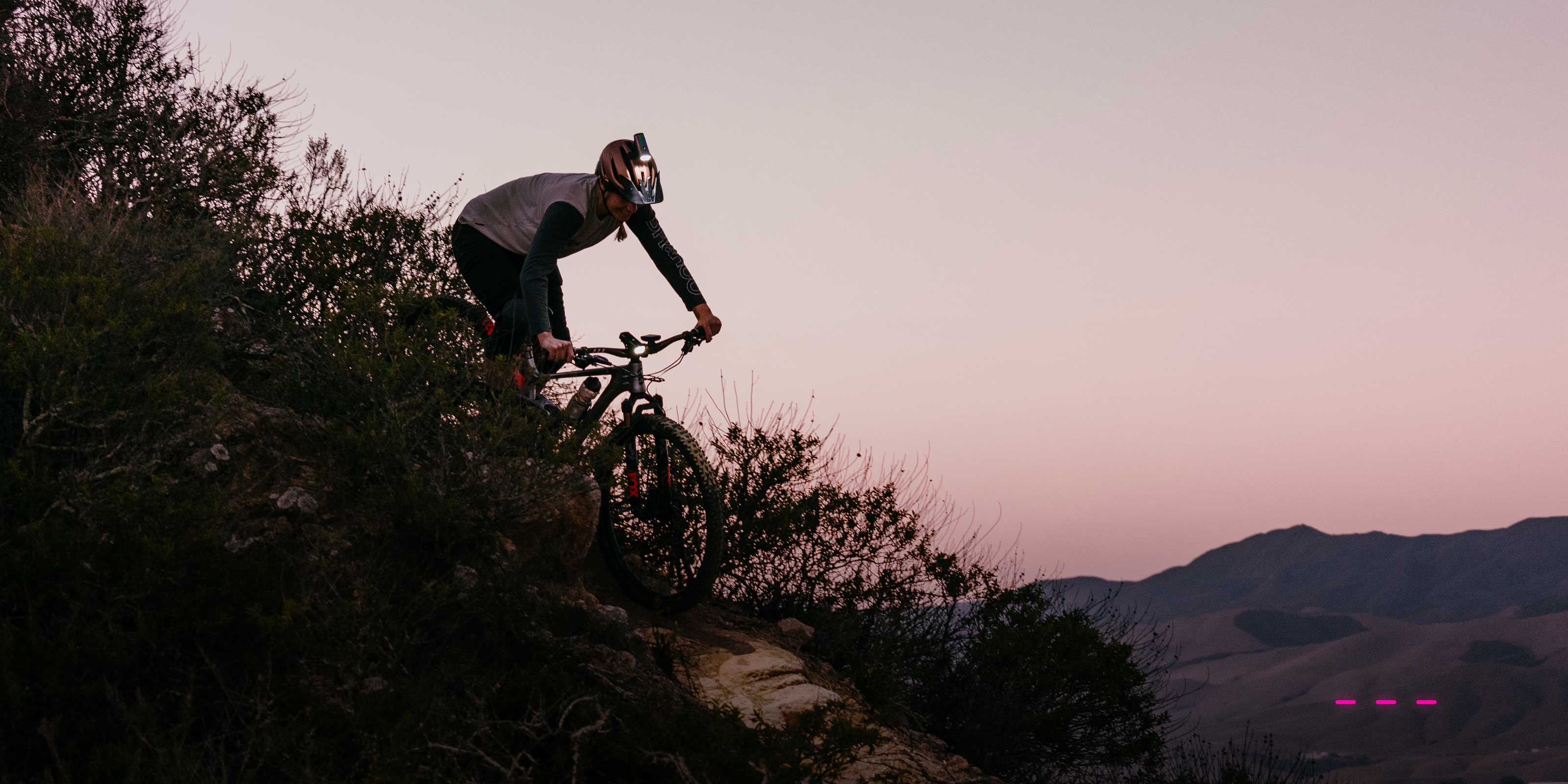 Mountain Biker with a helmet light on riding down a hill promoting a resolution to ride more in 2024
