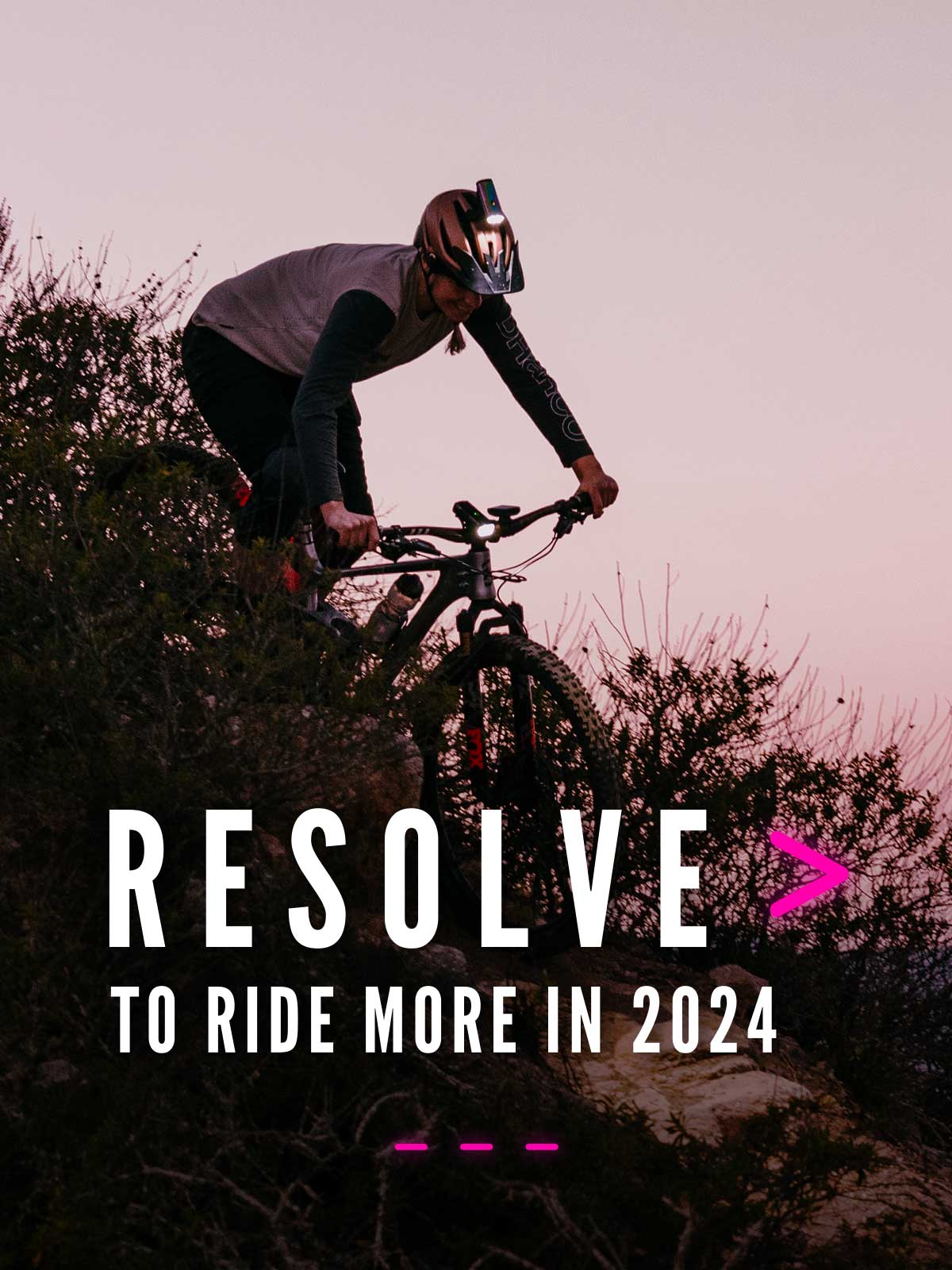 Bike rider descending down a mountain at dusk with lights with type that says 'Resolve to ride more in 2024'