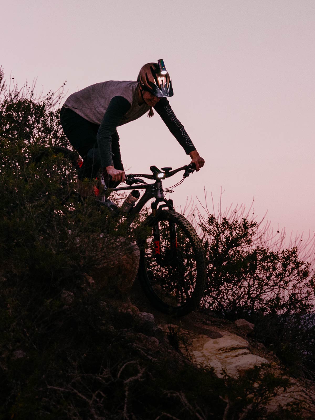 Mountain Biker with a helmet light on riding down a hill promoting a resolution to ride more in 2024