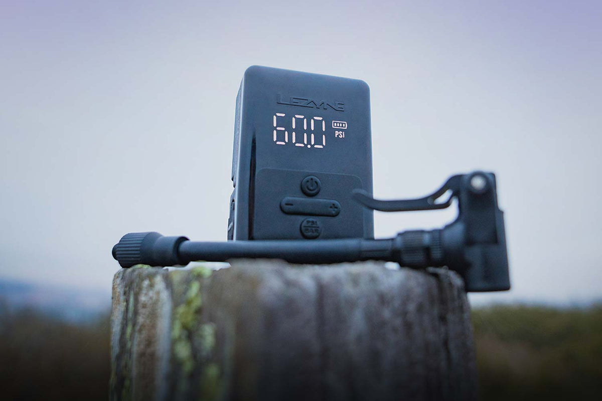 Lezyne E-Drive electric bike pump, sitting on a fence post with foggy background.